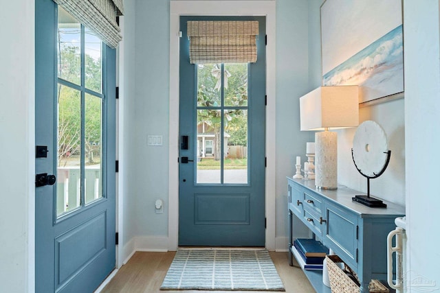 doorway to outside with plenty of natural light, light wood-style flooring, and baseboards