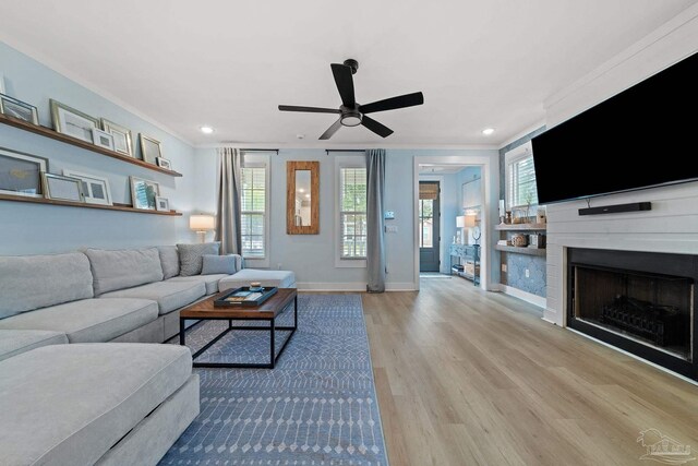 living area featuring a healthy amount of sunlight, crown molding, baseboards, and wood finished floors