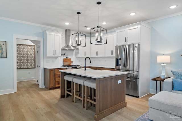 kitchen featuring light wood finished floors, stainless steel fridge with ice dispenser, wall chimney exhaust hood, a breakfast bar area, and light countertops