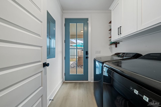 clothes washing area featuring light wood-type flooring, cabinet space, baseboards, and washing machine and clothes dryer