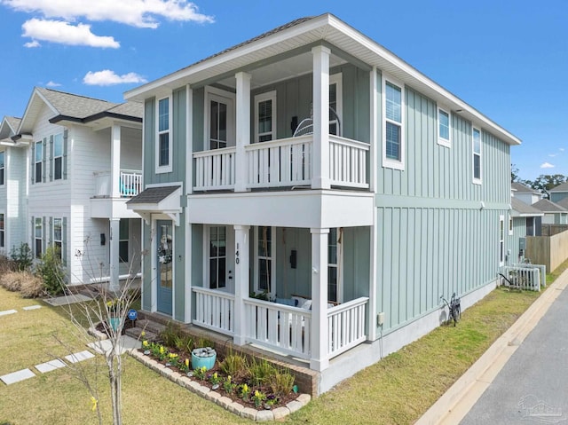 view of front facade with a porch, a front lawn, a balcony, and board and batten siding