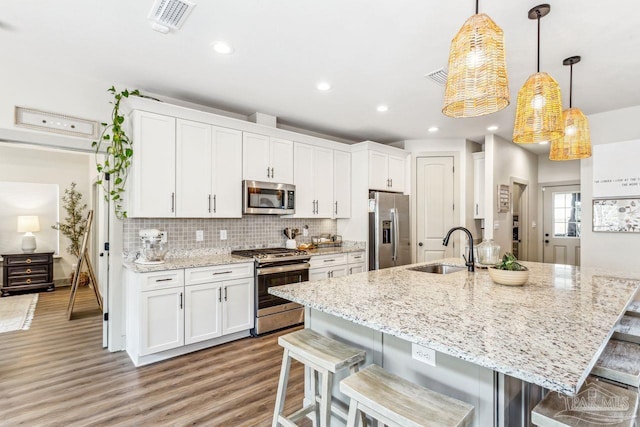 1058 Iron Forge Rd, Cantonment, FL 32533 - kitchen featuring stainless steel appliances, a sink, a breakfast bar area, white cabinetry, and recessed lighting