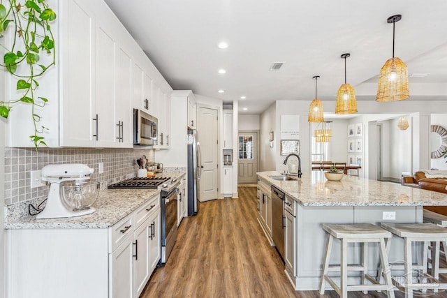 1058 Iron Forge Rd, Cantonment, FL 32533 - kitchen featuring stainless steel appliances, a sink, a breakfast bar, white cabinetry, and tasteful backsplash