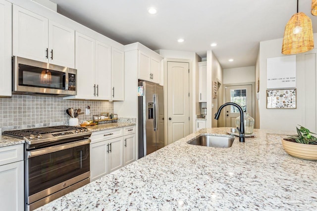 1058 Iron Forge Rd, Cantonment, FL 32533 - kitchen featuring appliances with stainless steel finishes, a sink, white cabinetry, backsplash, and hanging light fixtures