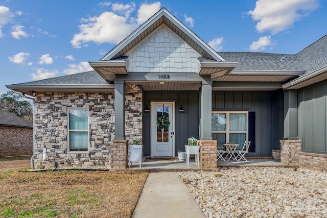 1058 Iron Forge Rd, Cantonment, FL 32533 - view of exterior entry with covered porch, roof with shingles, board and batten siding, and stone siding