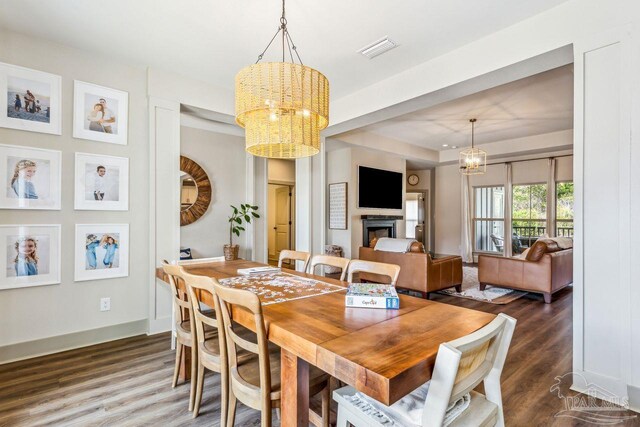 1058 Iron Forge Rd, Cantonment, FL 32533 - dining room featuring a chandelier, a fireplace, wood finished floors, and baseboards