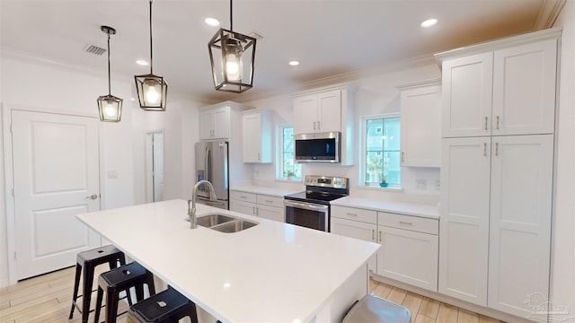 kitchen featuring sink, an island with sink, white cabinets, stainless steel appliances, and decorative light fixtures