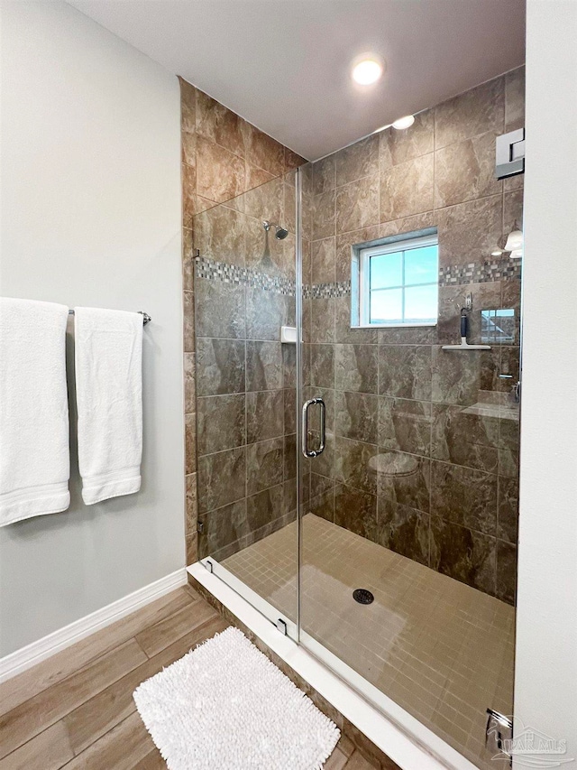 bathroom with a shower with shower door and hardwood / wood-style flooring