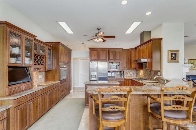 kitchen with a breakfast bar, kitchen peninsula, stainless steel appliances, and ceiling fan