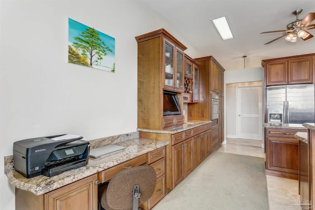 kitchen with light stone countertops, appliances with stainless steel finishes, and ceiling fan