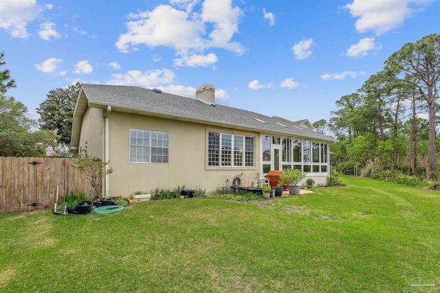 rear view of house with a yard and a sunroom