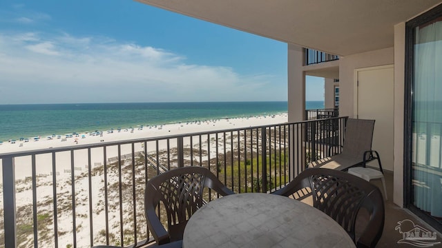 balcony featuring a water view, a view of the beach, and outdoor dining space