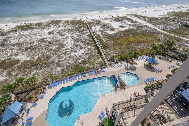 pool featuring a water view, a patio area, and a beach view