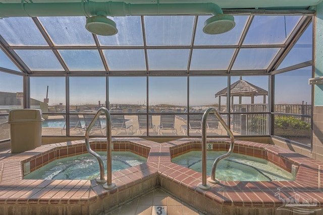 view of pool with glass enclosure and an indoor hot tub
