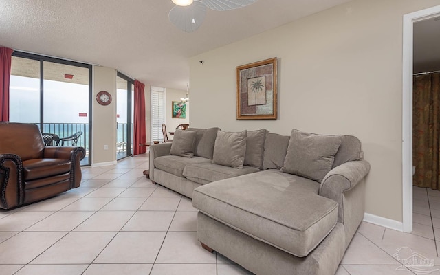 living room with light tile patterned floors, baseboards, and ceiling fan with notable chandelier