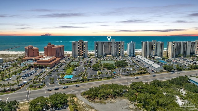 aerial view at dusk featuring a city view and a water view