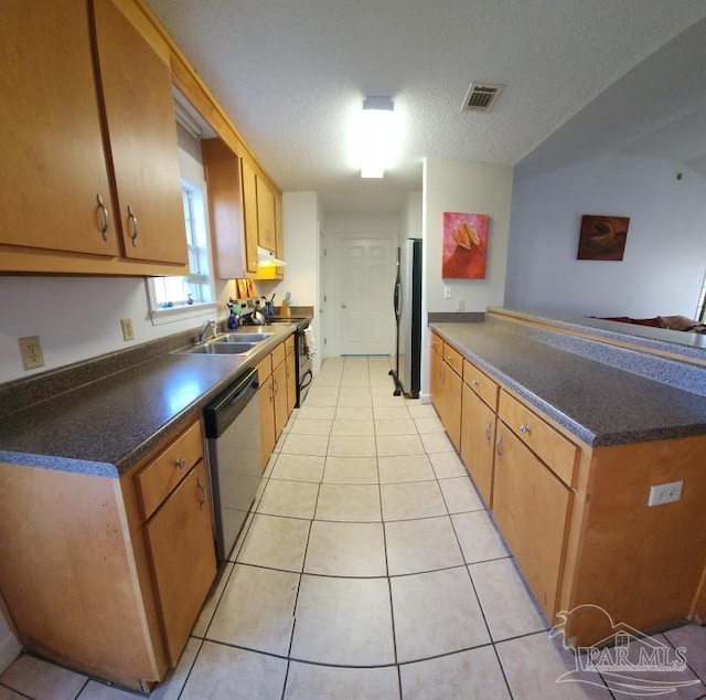 kitchen featuring sink, light tile patterned floors, kitchen peninsula, stainless steel appliances, and a textured ceiling