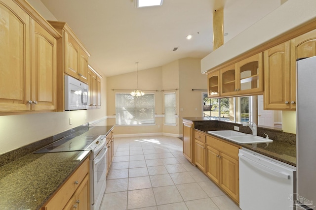 kitchen with appliances with stainless steel finishes, vaulted ceiling, sink, light tile patterned floors, and an inviting chandelier