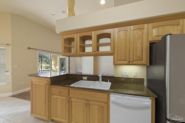 kitchen featuring stainless steel refrigerator, sink, kitchen peninsula, white dishwasher, and dark stone counters