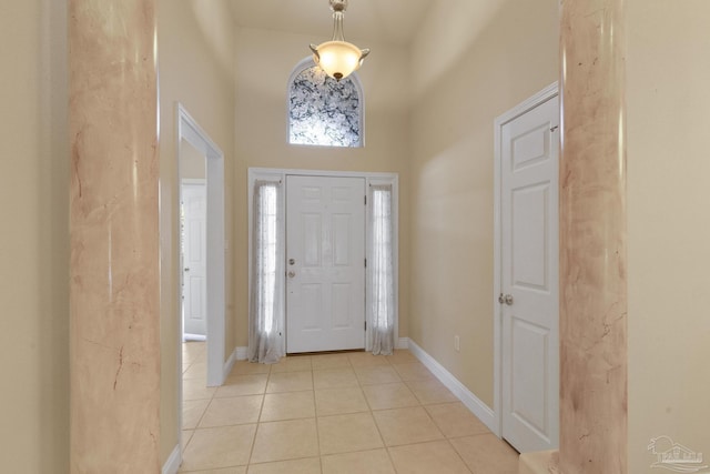 foyer entrance featuring light tile patterned floors and a towering ceiling