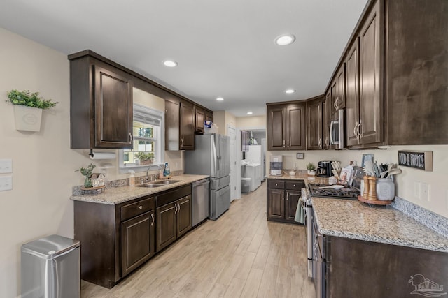 kitchen with a sink, dark brown cabinetry, light wood-type flooring, and stainless steel appliances