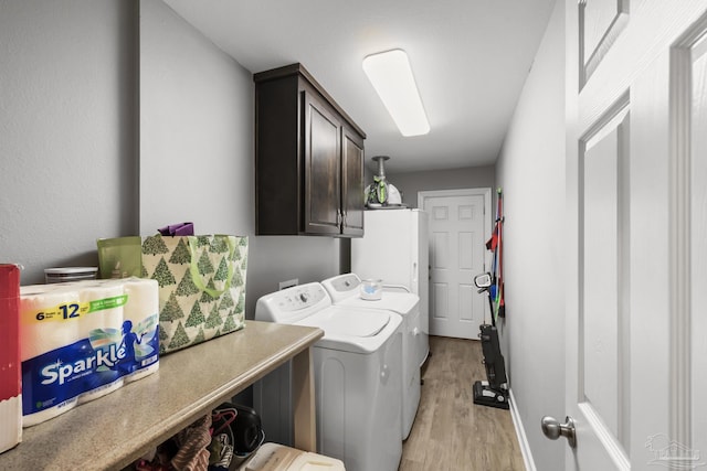 washroom with washer and clothes dryer, cabinet space, light wood-type flooring, and baseboards