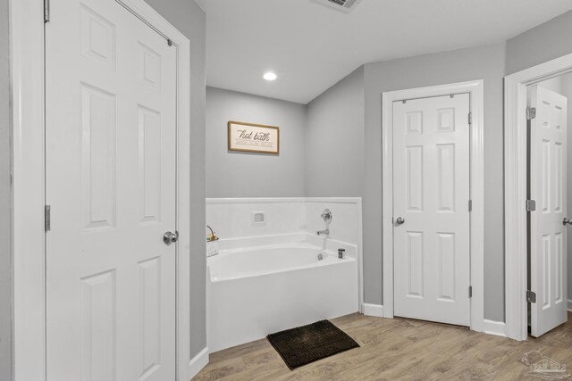 bathroom featuring visible vents, a garden tub, and wood finished floors