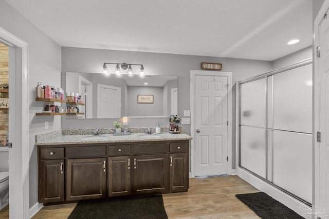 full bathroom with a sink, wood finished floors, and a stall shower