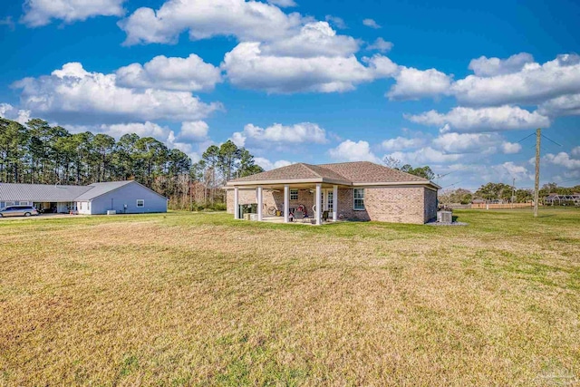 back of property with a patio, a lawn, and brick siding