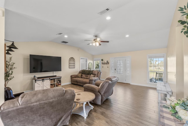 living area featuring a wealth of natural light, visible vents, wood finished floors, and vaulted ceiling