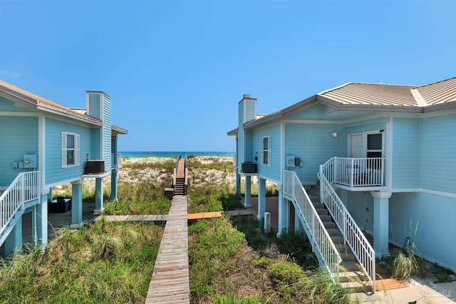 1299 Ft Pickens Rd Unit 6, Pensacola Beach, FL 32561 - view of side of home featuring a water view, a standing seam roof, central AC, metal roof, and stairs
