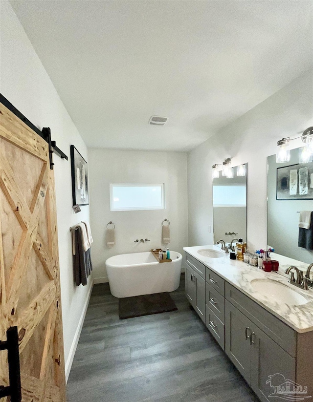 1315 W Scott St, Pensacola, FL 32501 - bathroom featuring a soaking tub, visible vents, wood finished floors, and a sink