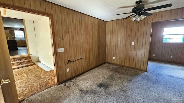 carpeted empty room featuring ceiling fan and wood walls