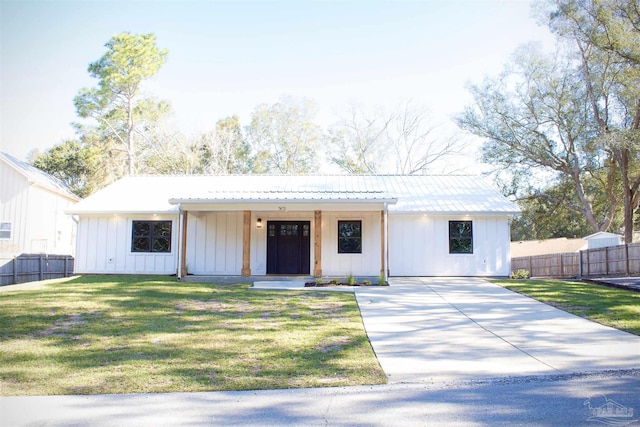 modern farmhouse style home with metal roof, a front lawn, board and batten siding, and fence