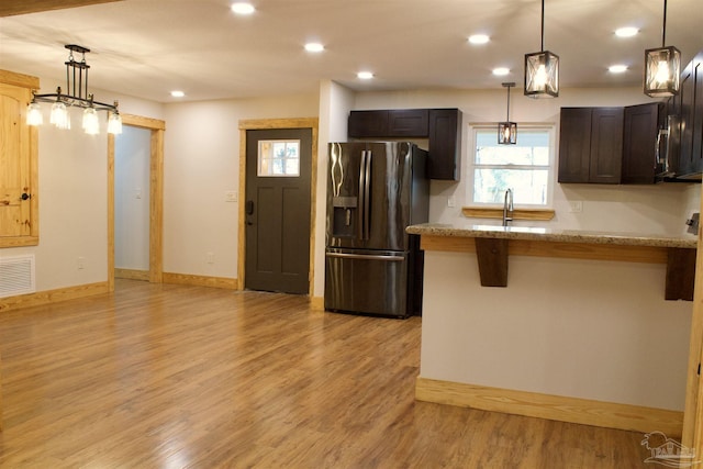 kitchen featuring dark brown cabinetry, recessed lighting, visible vents, refrigerator with ice dispenser, and light wood-type flooring