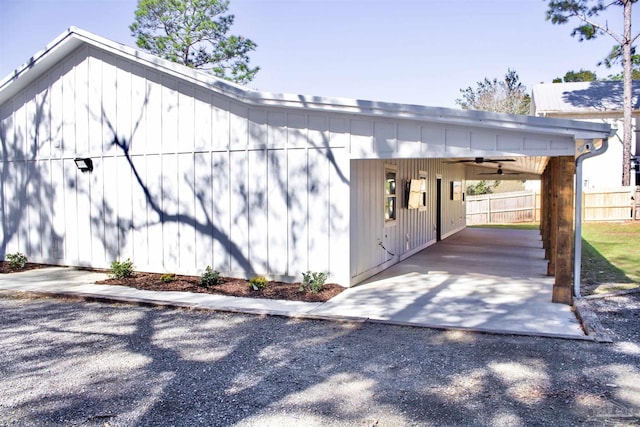 view of home's exterior featuring driveway, a carport, fence, and a ceiling fan