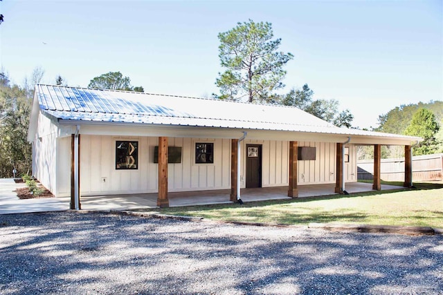 exterior space featuring metal roof, board and batten siding, and fence