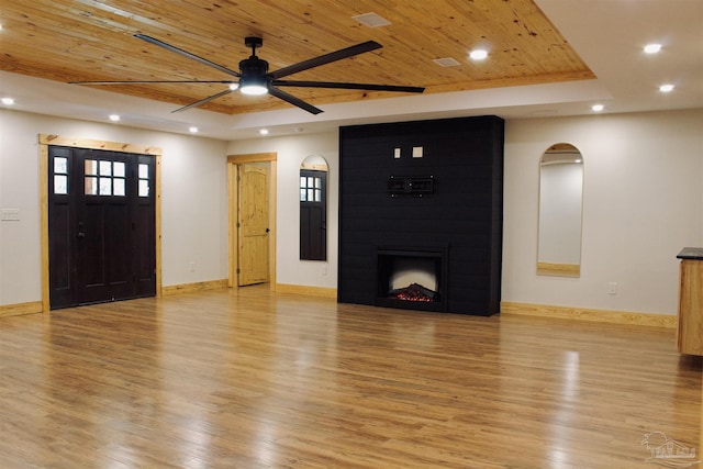 unfurnished living room featuring light wood-style floors, wood ceiling, a raised ceiling, and a fireplace