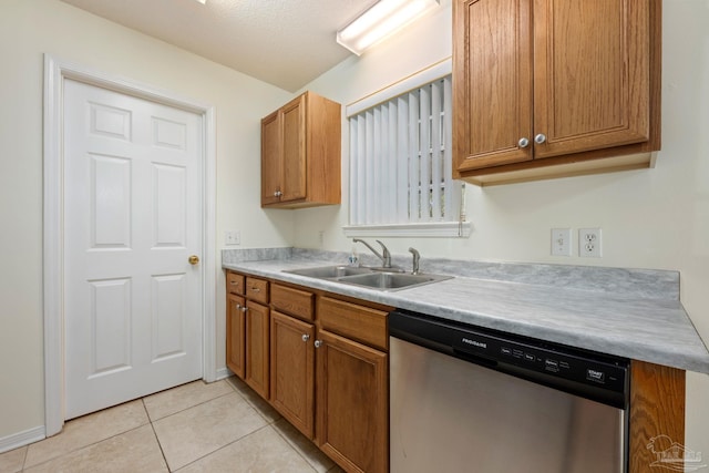 kitchen with sink, light tile patterned floors, stainless steel dishwasher, and a textured ceiling