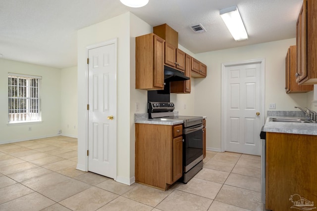 kitchen featuring stainless steel electric range oven, sink, light tile patterned flooring, and a textured ceiling