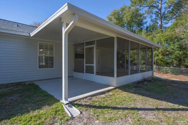 rear view of property featuring a lawn, a patio area, and a sunroom