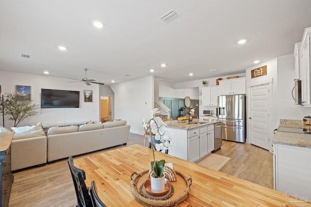 dining room featuring ceiling fan, sink, and light hardwood / wood-style flooring