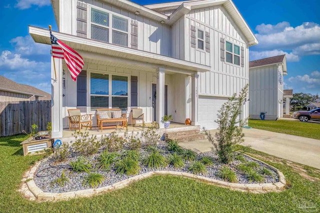 multi unit property featuring a garage, covered porch, and a front lawn