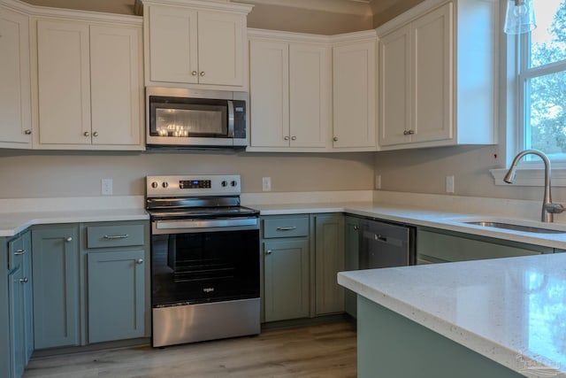 kitchen with sink, white cabinetry, light hardwood / wood-style flooring, and stainless steel appliances