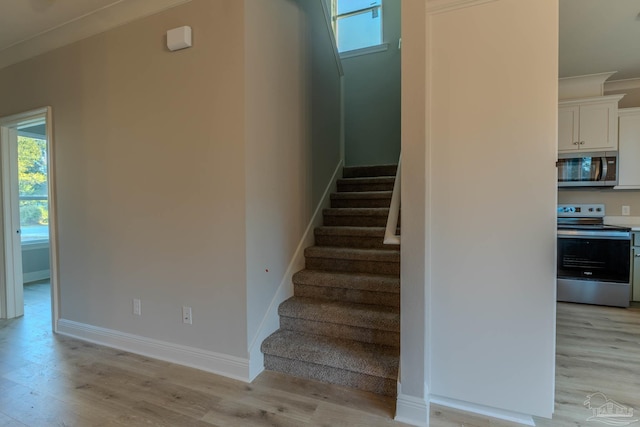 stairway featuring crown molding and wood-type flooring