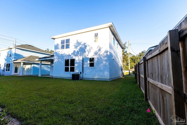 rear view of property with central AC and a yard