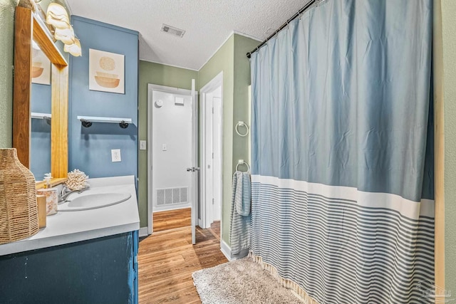 bathroom featuring hardwood / wood-style flooring, vanity, and a textured ceiling