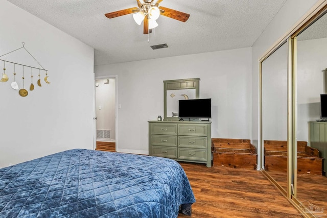 bedroom featuring dark hardwood / wood-style flooring, ceiling fan, a closet, and a textured ceiling