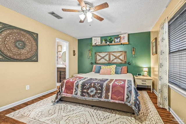 bedroom with hardwood / wood-style flooring, ensuite bath, ceiling fan, and a textured ceiling