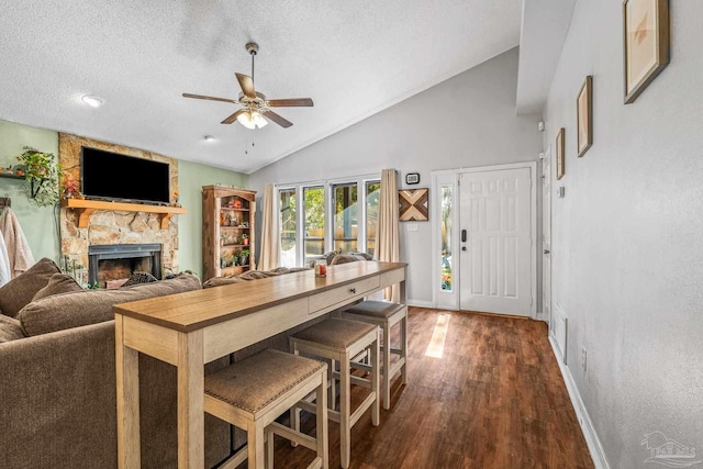 dining room featuring vaulted ceiling, dark hardwood / wood-style flooring, a textured ceiling, and a fireplace